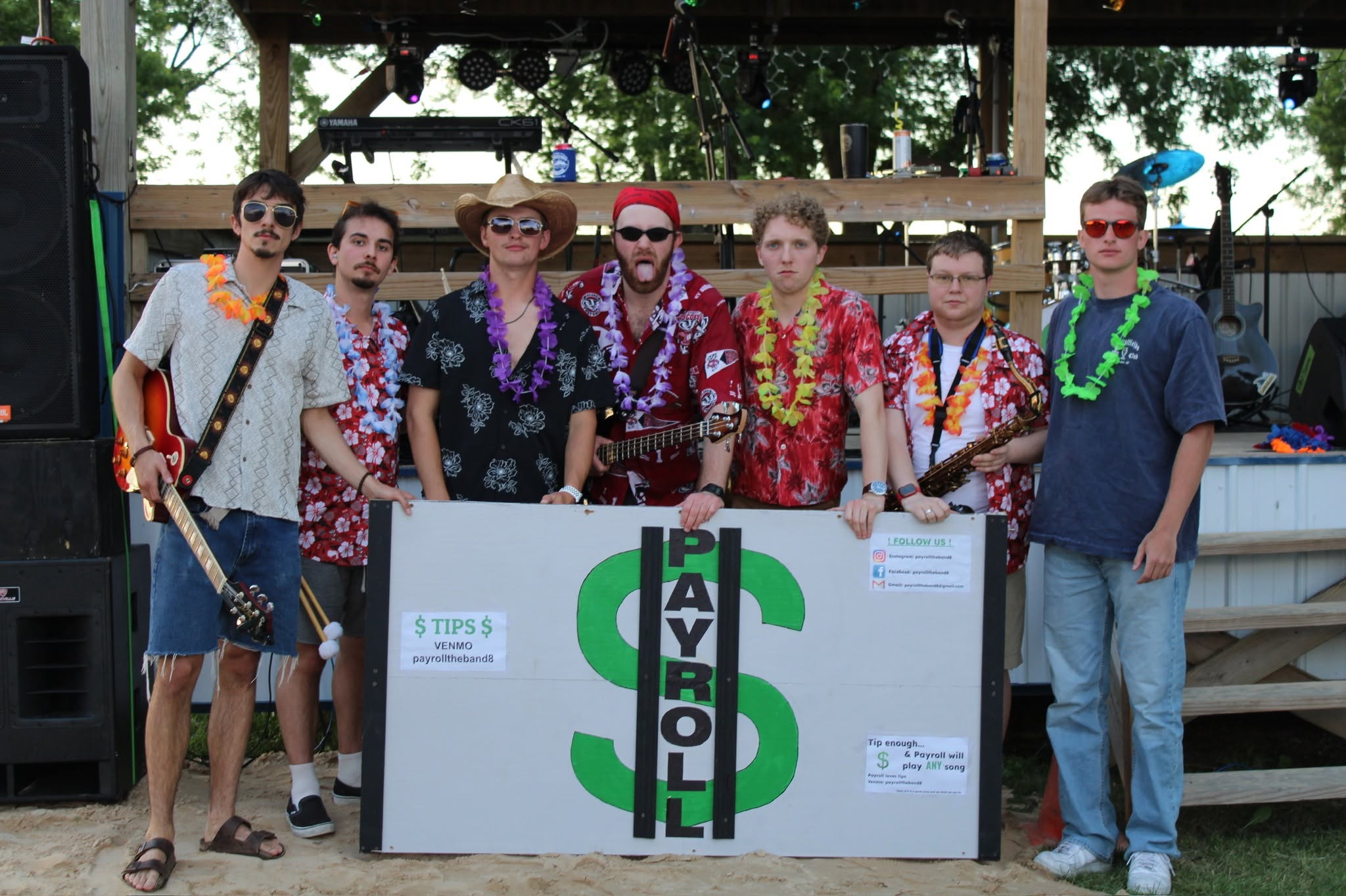 Seven members of the band Payroll in tropical shirts and leis pose with a sign for Venmo payrolltheband8